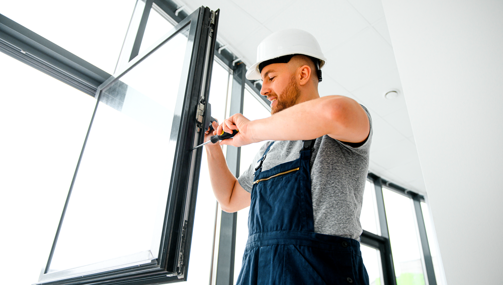 jeune homme seduisant installant baie vitree sur chantier construction nouvelle maison